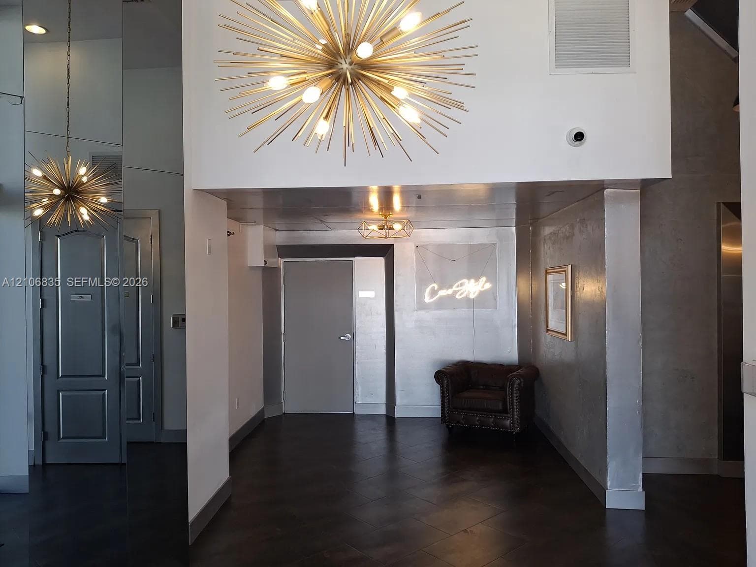 Mid-century modern starburst chandelier, floor-to-ceiling mirror paneling, metallic-finish wall treatments, and dark large-format tile flooring