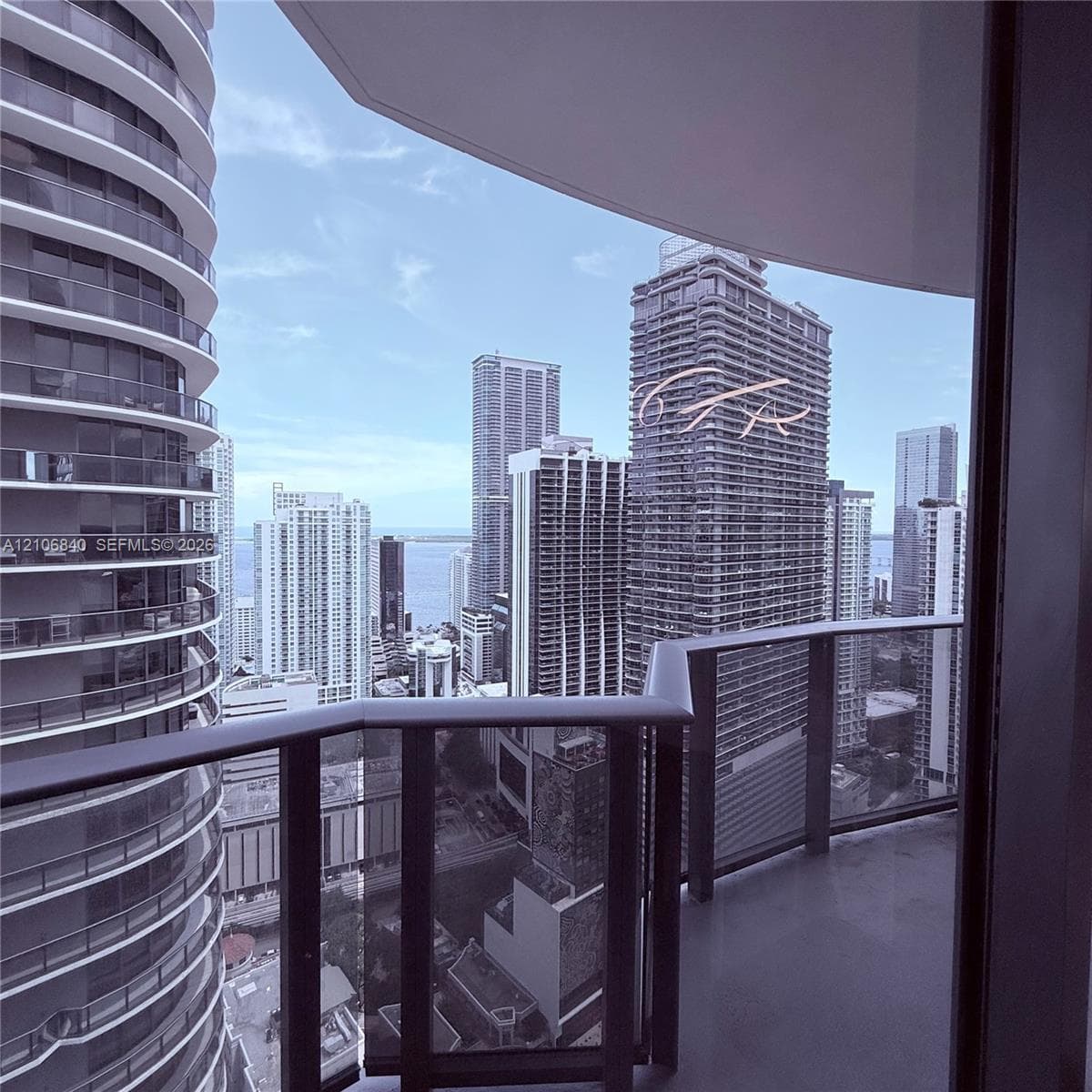 Covered private balcony featuring glass railings and panoramic urban skyline scenery