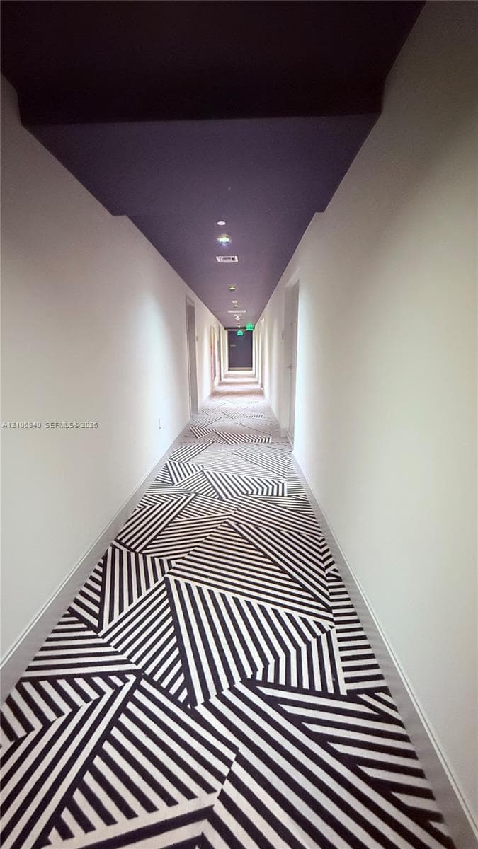 Hallway featuring geometric patterned carpeting, a deep-toned ceiling, and recessed lighting