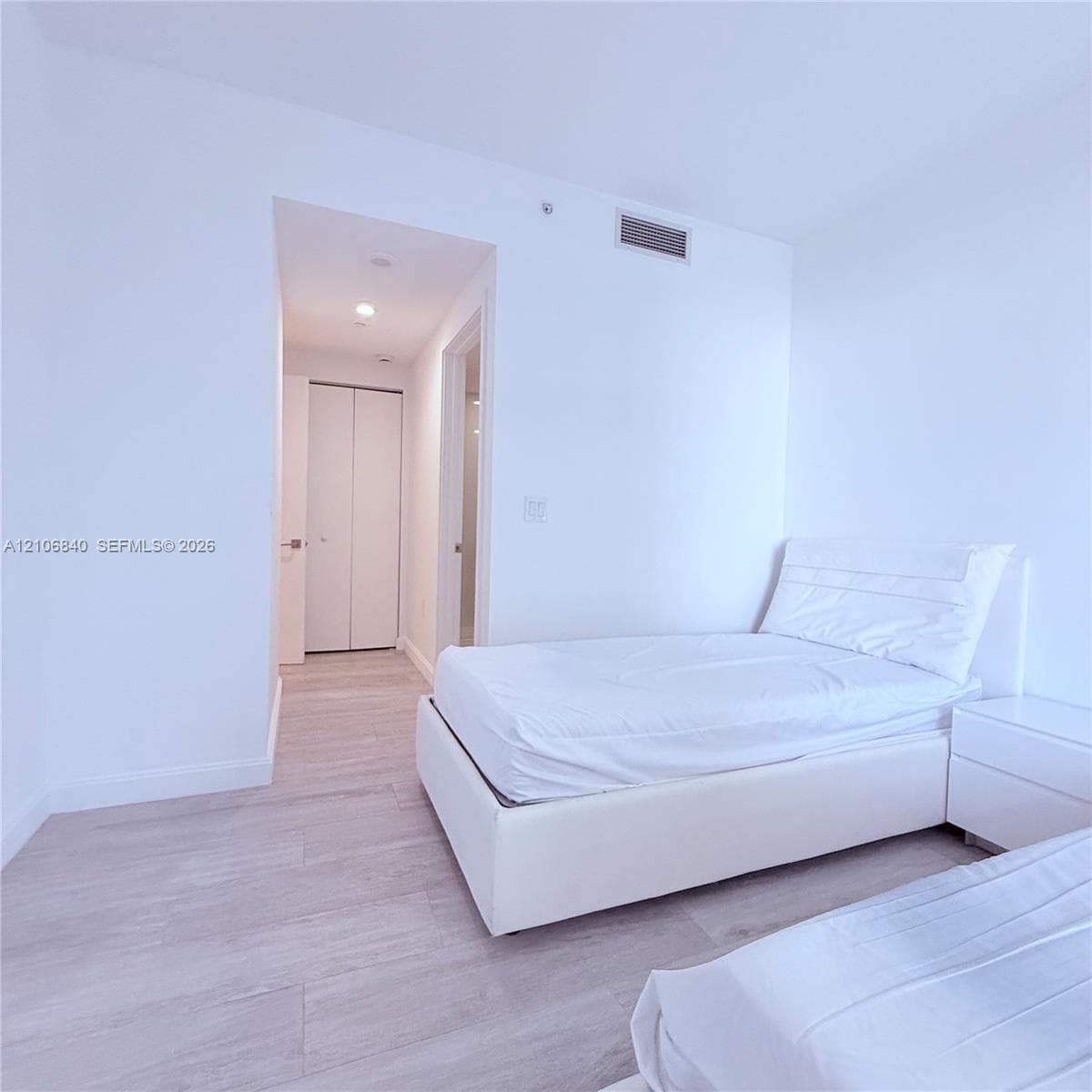 Neutral-toned wood-finish flooring, recessed lighting, and a dual-panel closet door