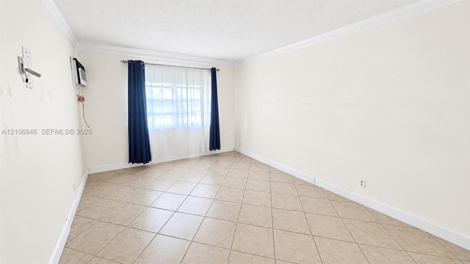 Neutral-toned room featuring diagonal-set tile flooring, crown molding, and a dual-panel window with a mounted wall air conditioning unit