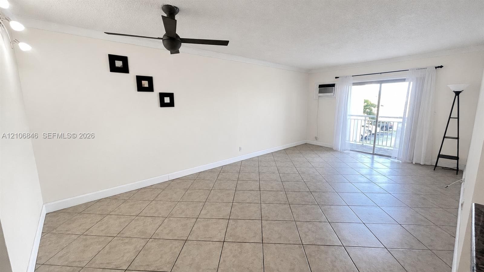 Tile flooring, ceiling fan, wall-mounted light fixtures, and sliding glass door with balcony access