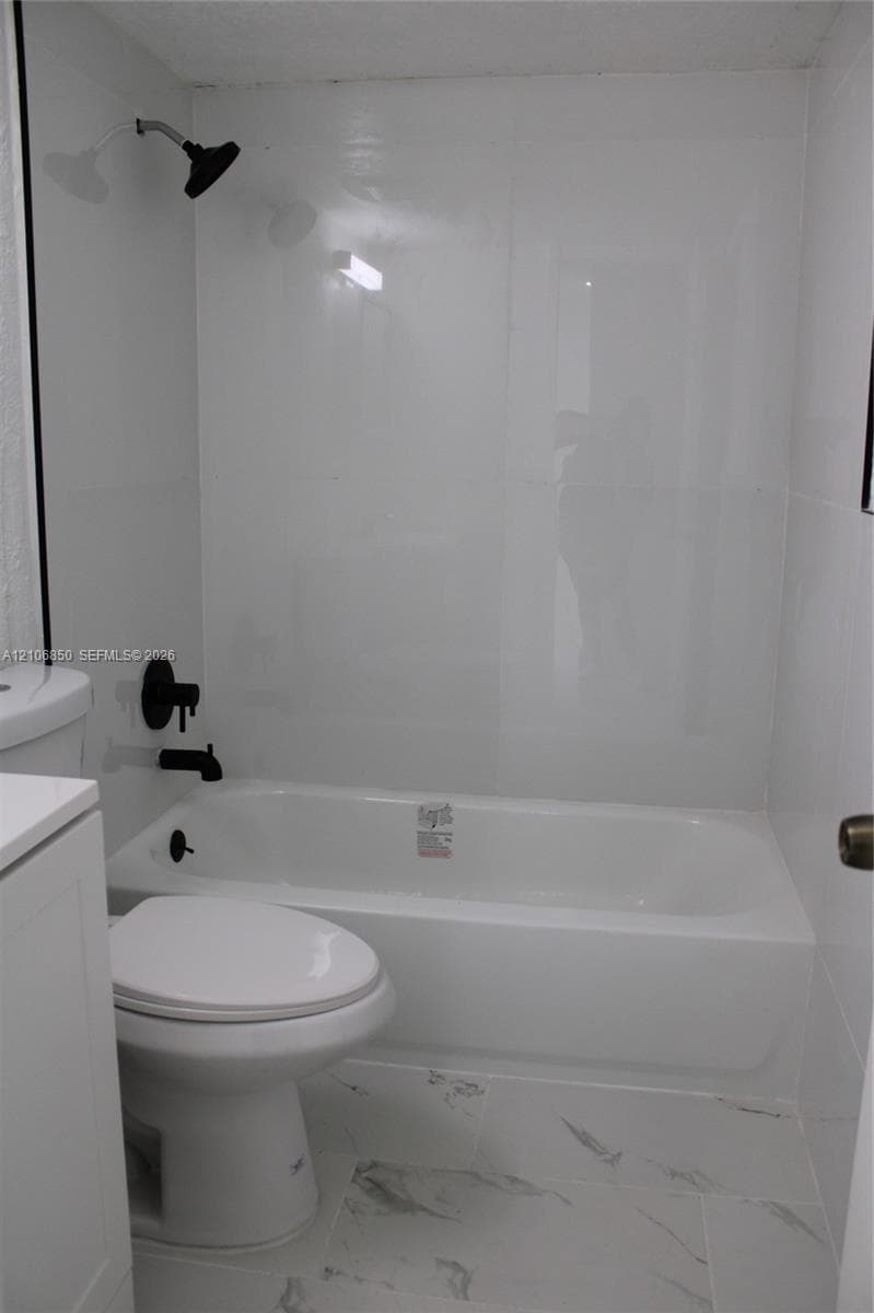 Bathroom featuring a porcelain tub with high-gloss wall surround, matte black rainfall showerhead, matching matte black plumbing fixtures, and patterned tile flooring