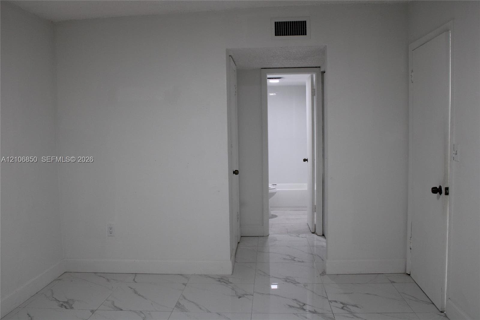 Polished large-format tile flooring with marble-finish detailing, solid-core interior doors, and neutral wall finishes