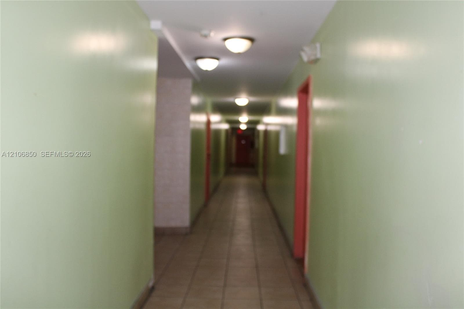 Interior corridor featuring tiled flooring, painted walls, and ceiling-mounted dome light fixtures