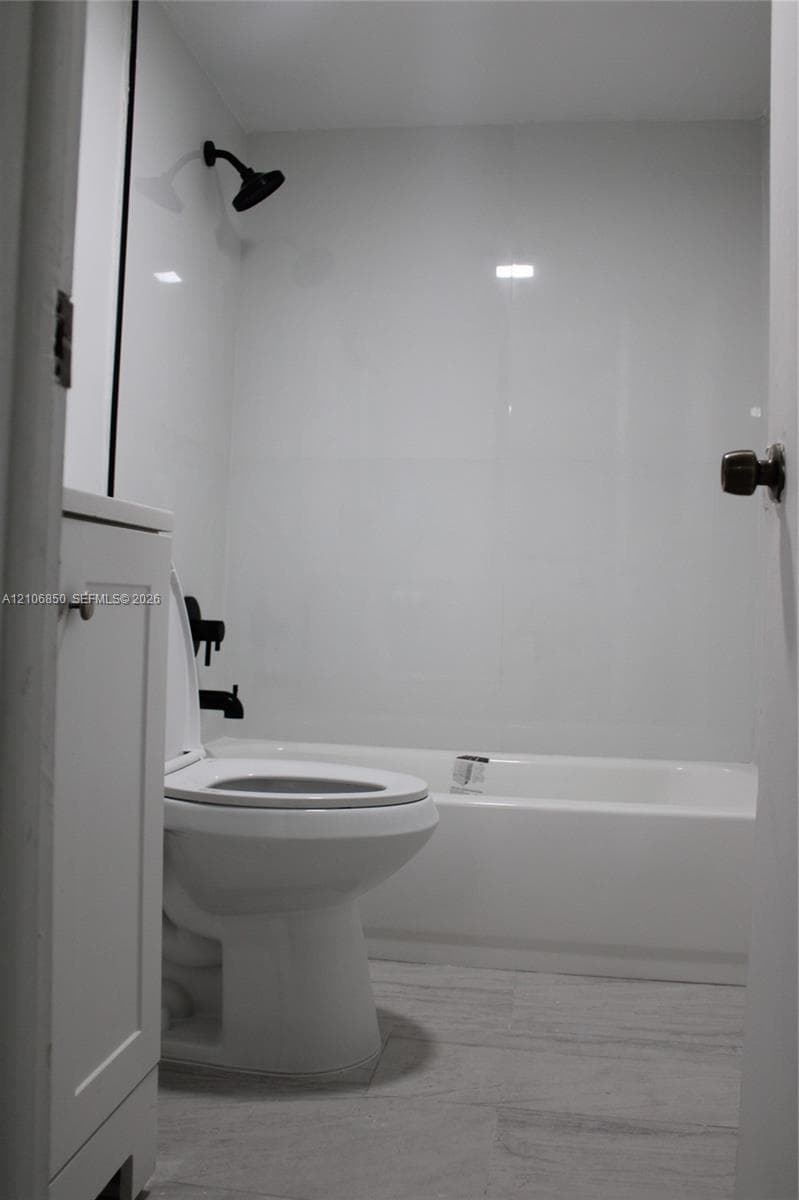 Full bathroom featuring a white bathtub, smooth wall panels, matte black shower head and hardware, and wood-finish flooring