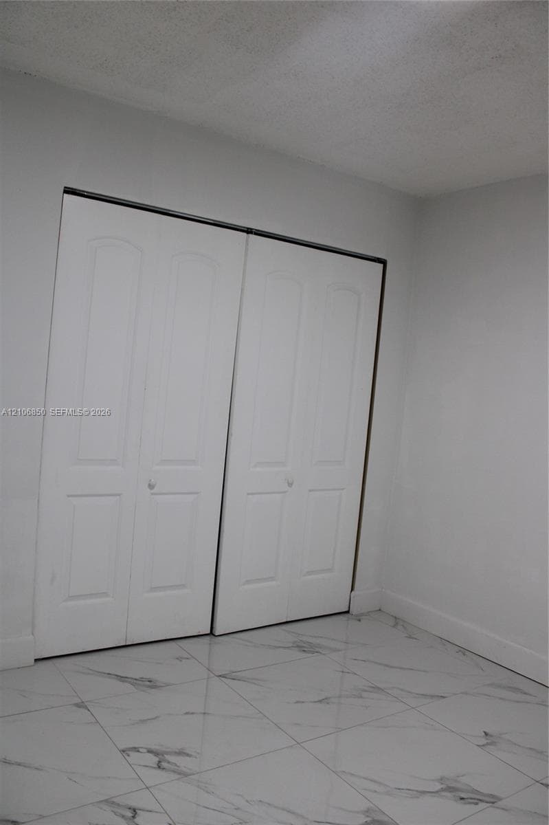 Large-format stone-patterned tile flooring and dual-panel white closet doors