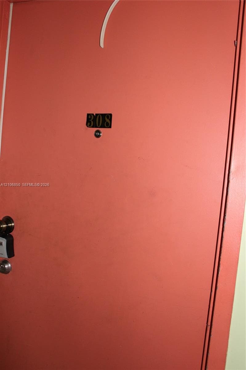 Solid-core entry door featuring a matte finish, brass-toned numerical identification plate, and integrated door viewer