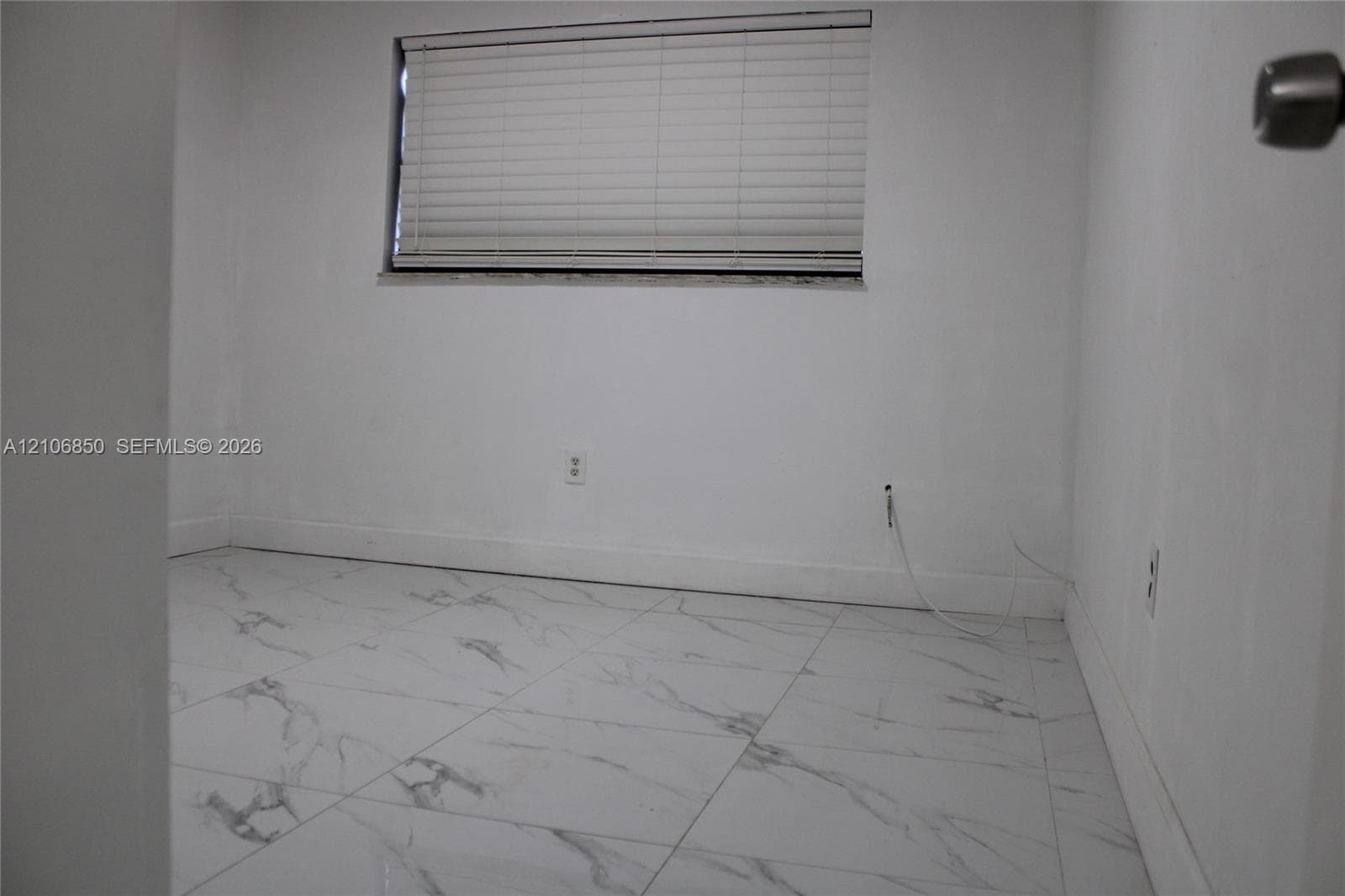 Interior space featuring white stone-finish tile flooring and an integrated horizontal window blind