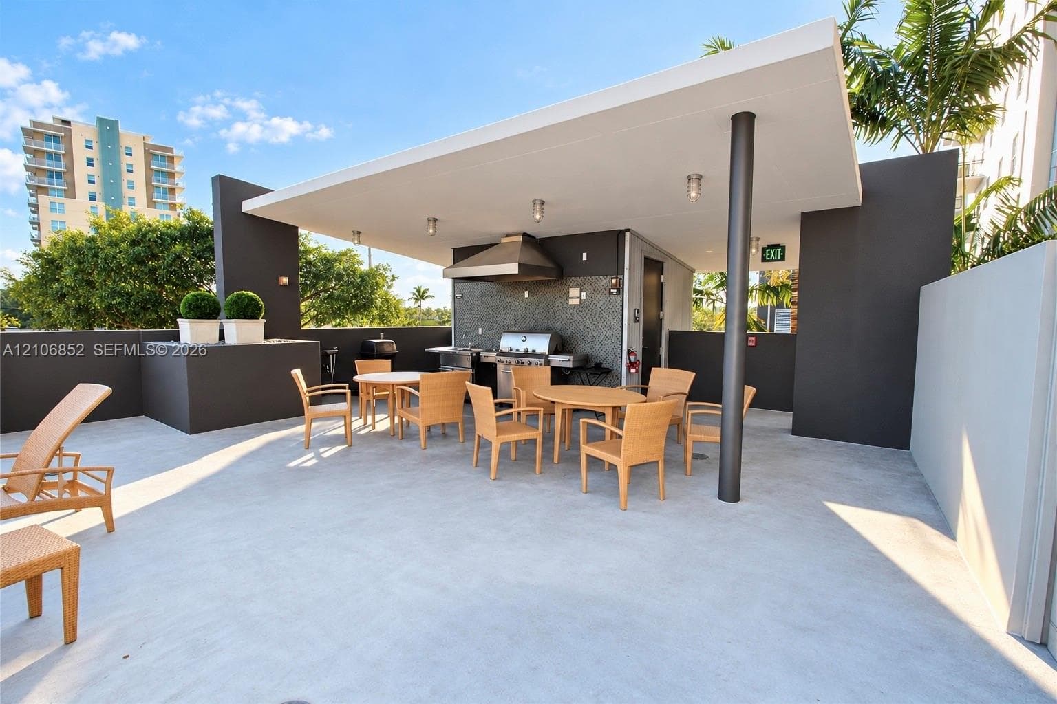 Outdoor terrace featuring a concrete patio, covered grilling station with stainless steel appliances, stone-tile backsplash, and recessed ceiling lighting