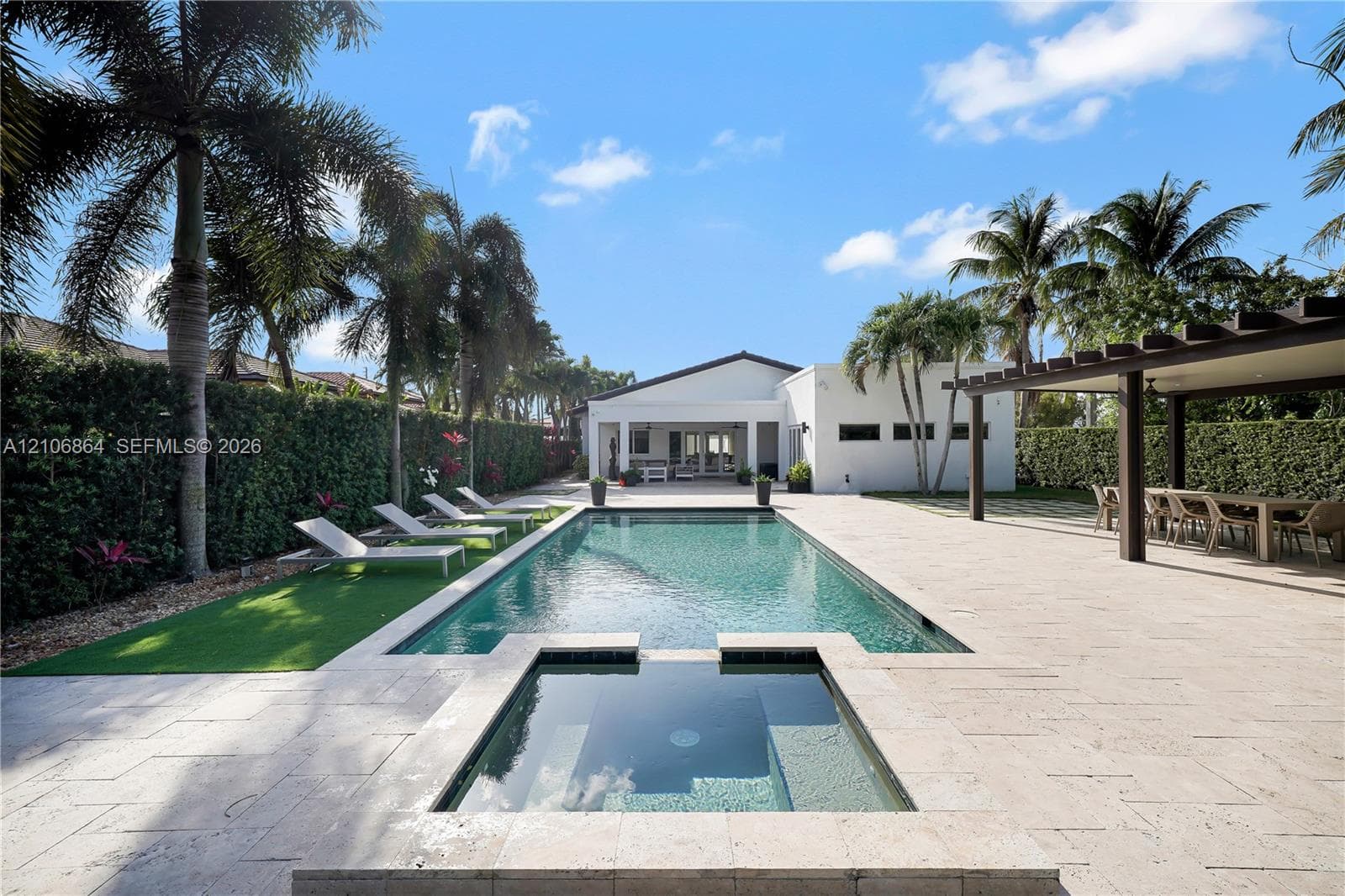 Expansive grounds featuring a manicured lawn, perimeter hedge fencing, and mature palm trees