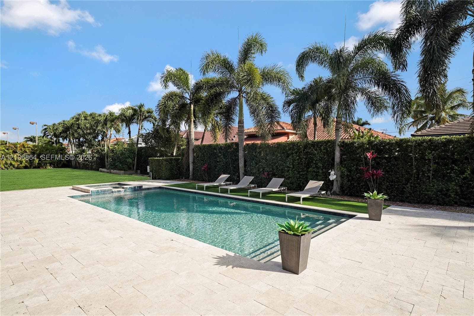 Aerial perspective of a multi-residence property featuring tiled roofing, rectangular in-ground swimming pools, paved exterior hardscaping, and mature palm landscaping