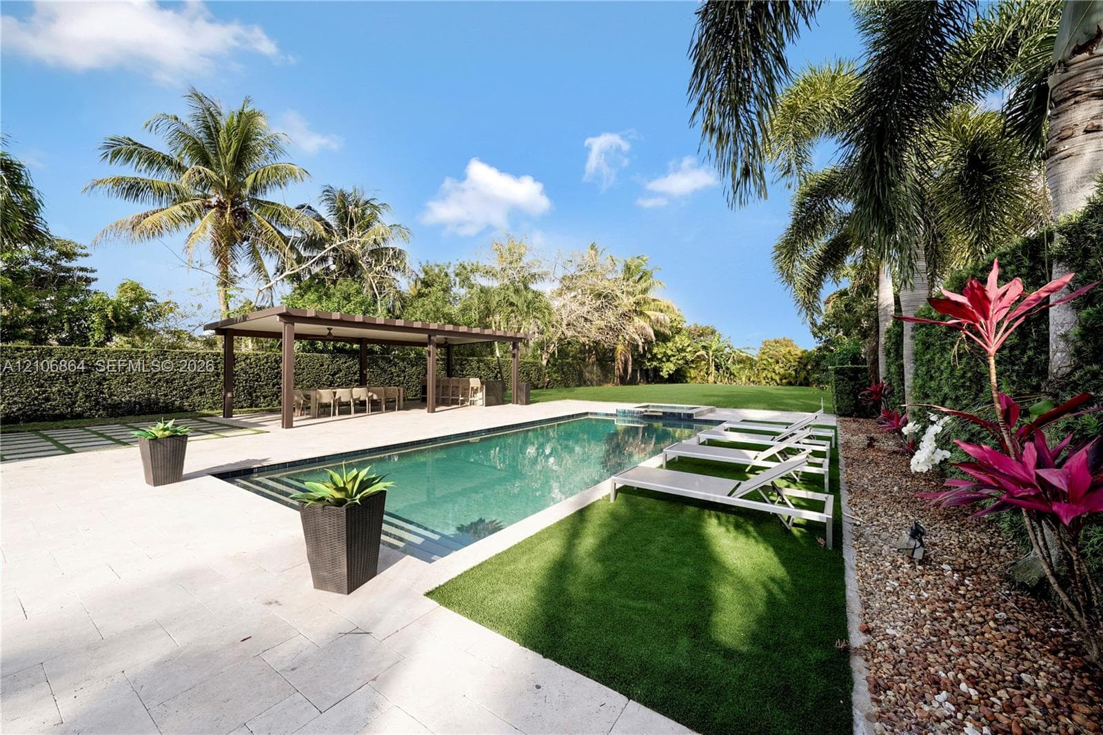 Single-story exterior featuring a concrete driveway, two-car garage, manicured lawn, and mature palm trees