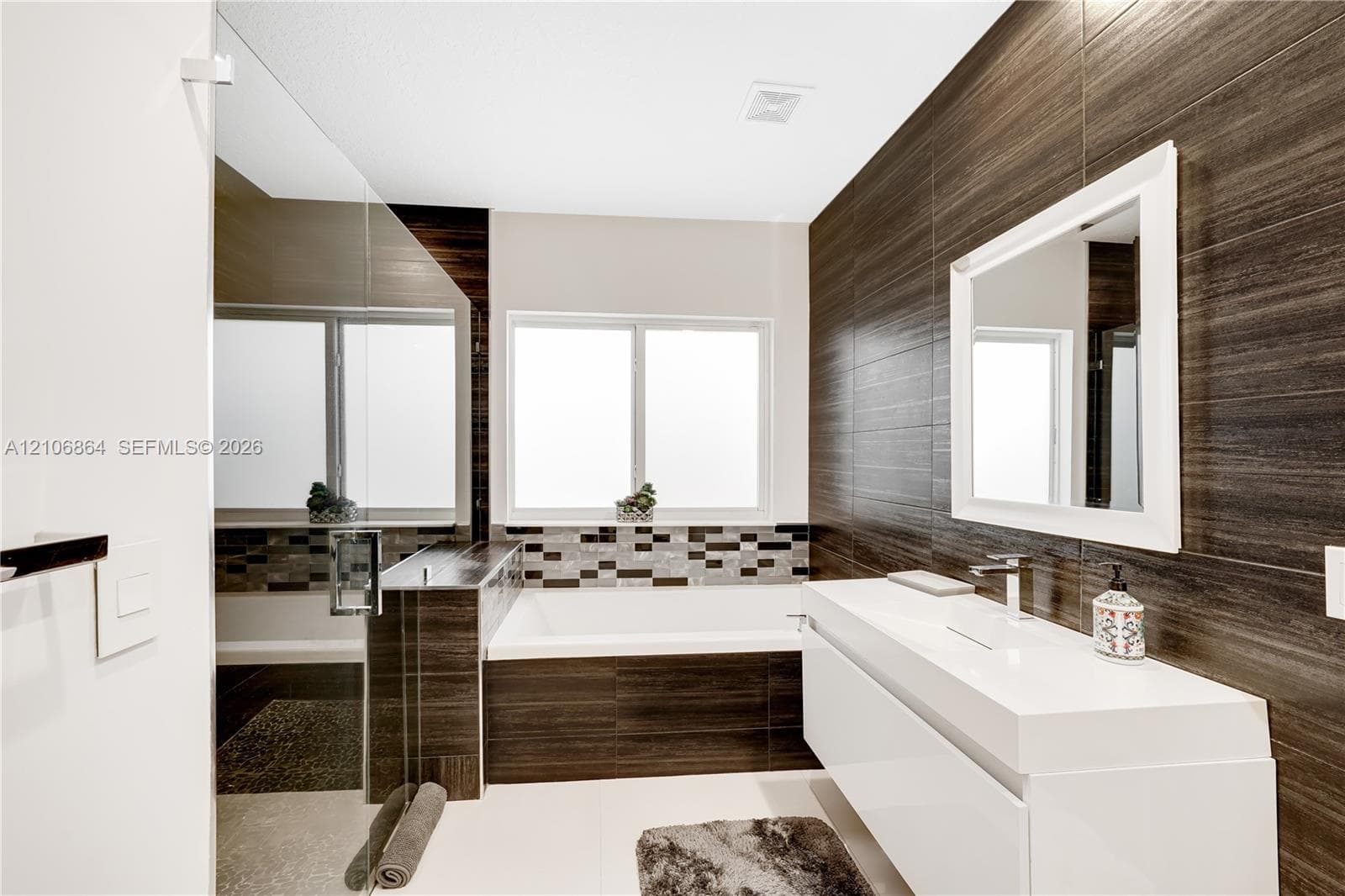 Neutral-toned interior featuring high ceilings, a ceiling fan with integrated lighting, polished flooring, and a large window