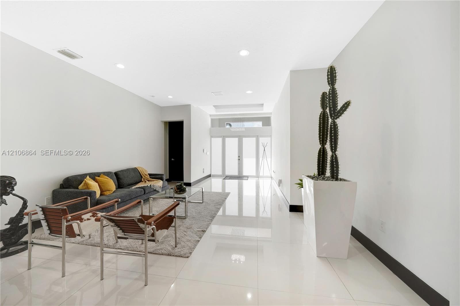 Open-concept interior featuring large-format tile flooring, recessed lighting, a stone-accent wall, and a kitchen island with built-in cabinetry