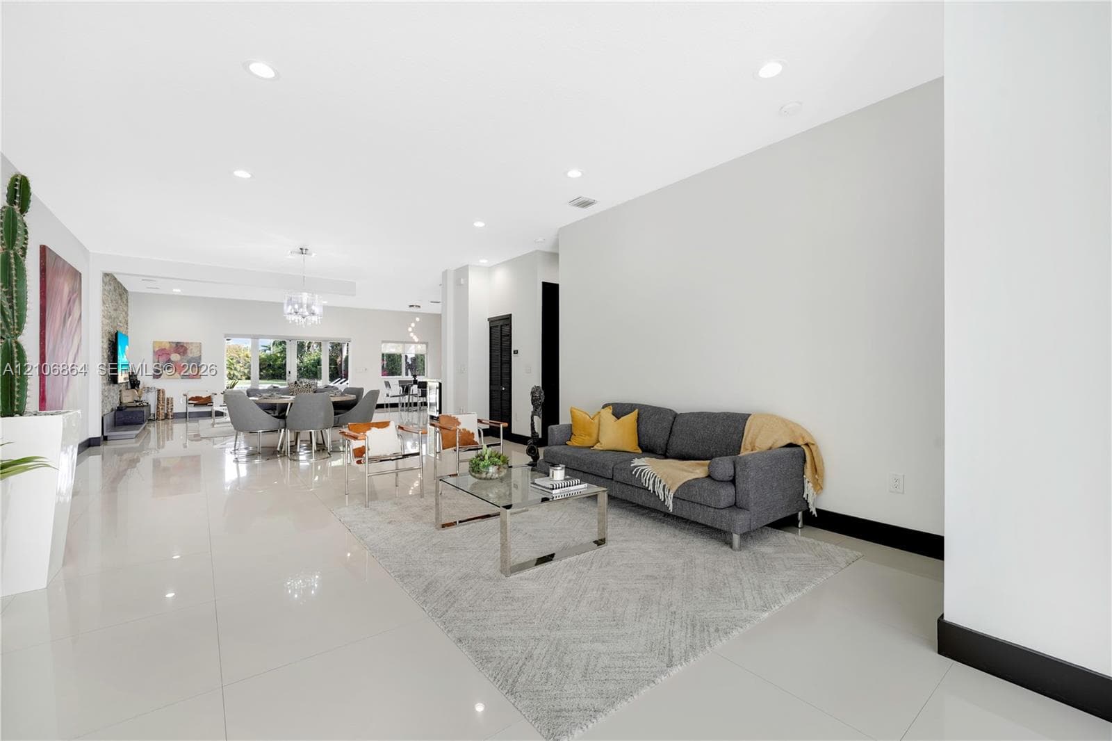 Open-concept interior featuring large-format tile flooring, a stone-accent wall, recessed lighting, and a crystal chandelier