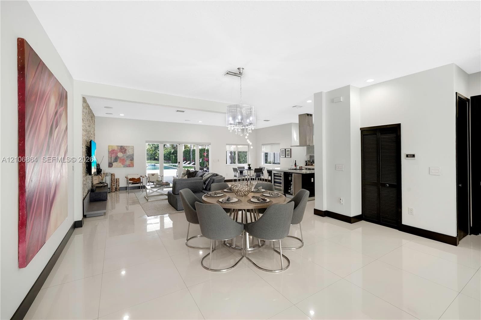Open-concept living space featuring high-gloss cabinetry, stainless steel appliances, stone-veneer accent wall, and porcelain tile flooring