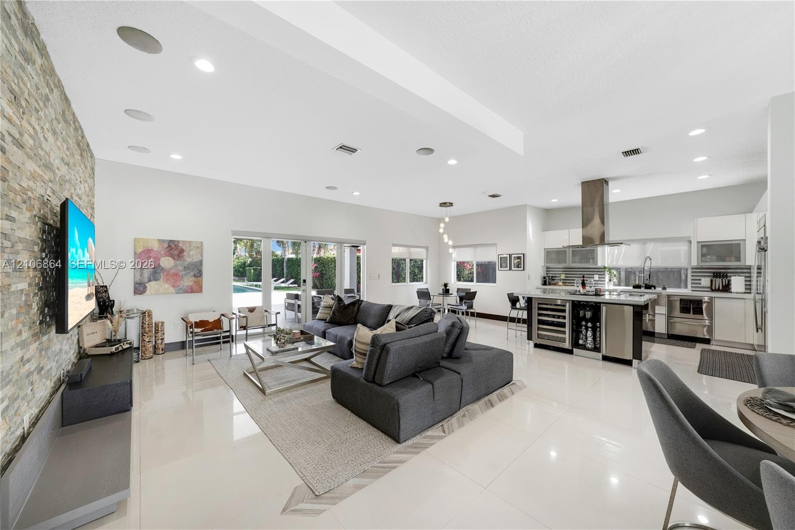 Living area featuring stacked stone accent wall, large-format tile flooring, recessed lighting, and multi-panel sliding glass doors
