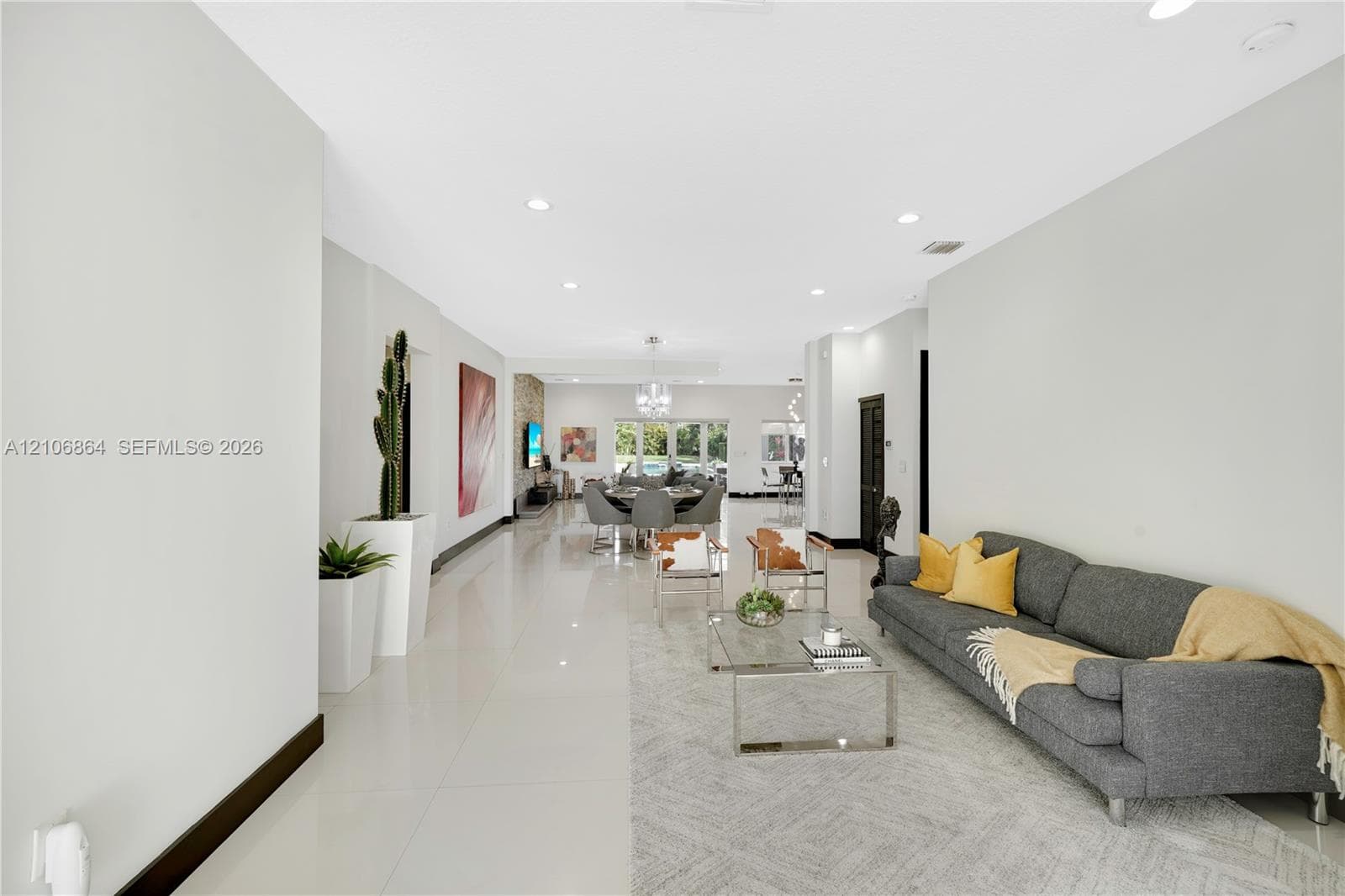 Open-concept living space featuring high ceilings with recessed lighting, crisp white wall finishes, polished hard-surface flooring, and high-contrast dark door frames