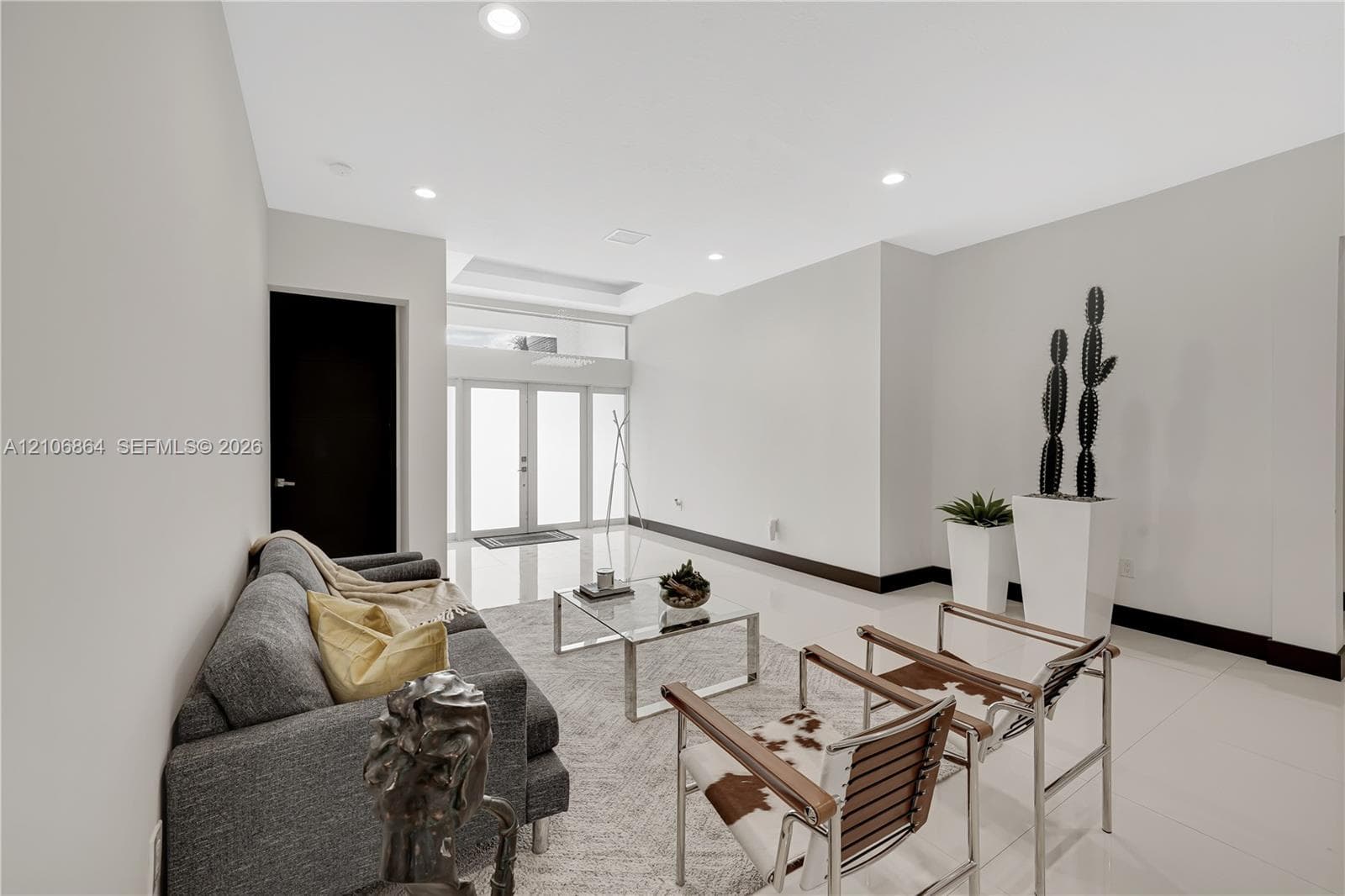 Open-concept living space featuring a floor-to-ceiling stone-veneer accent wall, large-format tile flooring, recessed lighting, and multi-panel sliding glass doors