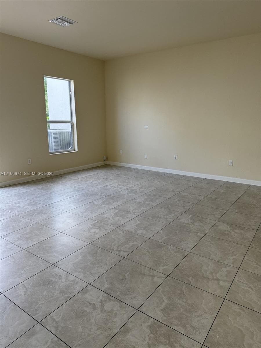 Neutral-toned interior space featuring large-format tile flooring and a vertical window