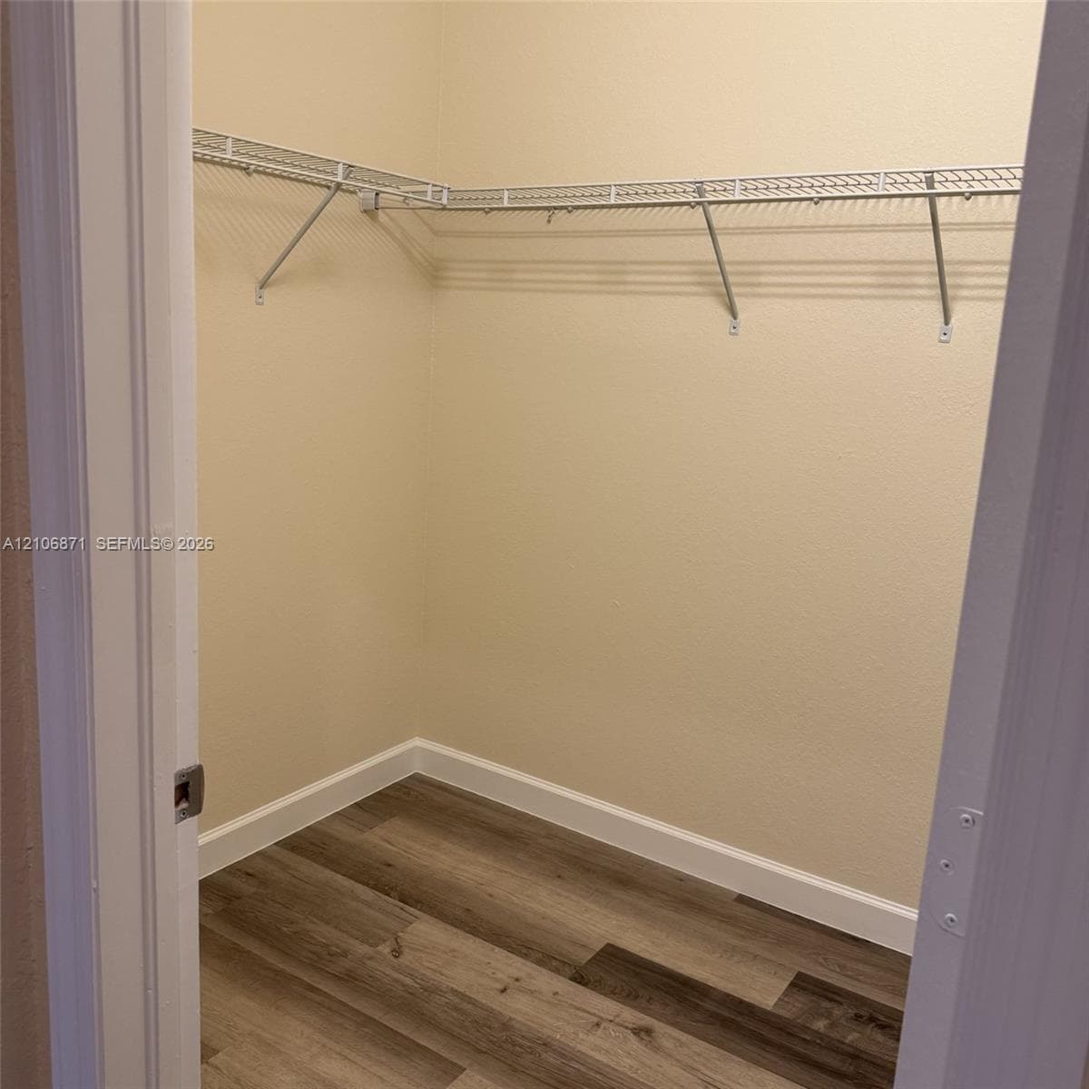 Storage space featuring wood-finish flooring and wall-mounted wire shelving
