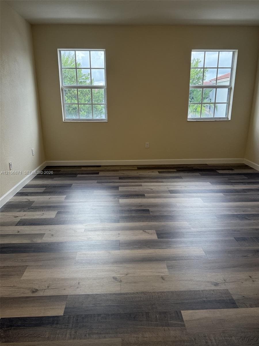 Multi-tone wood-finish flooring, two dual-pane windows with grid detailing, and neutral wall color