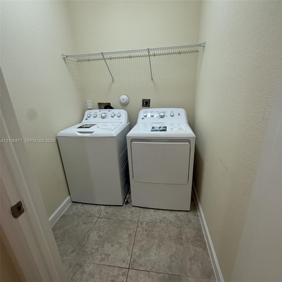 Laundry area featuring large-format ceramic tile flooring, neutral wall paint, and overhead wire shelving