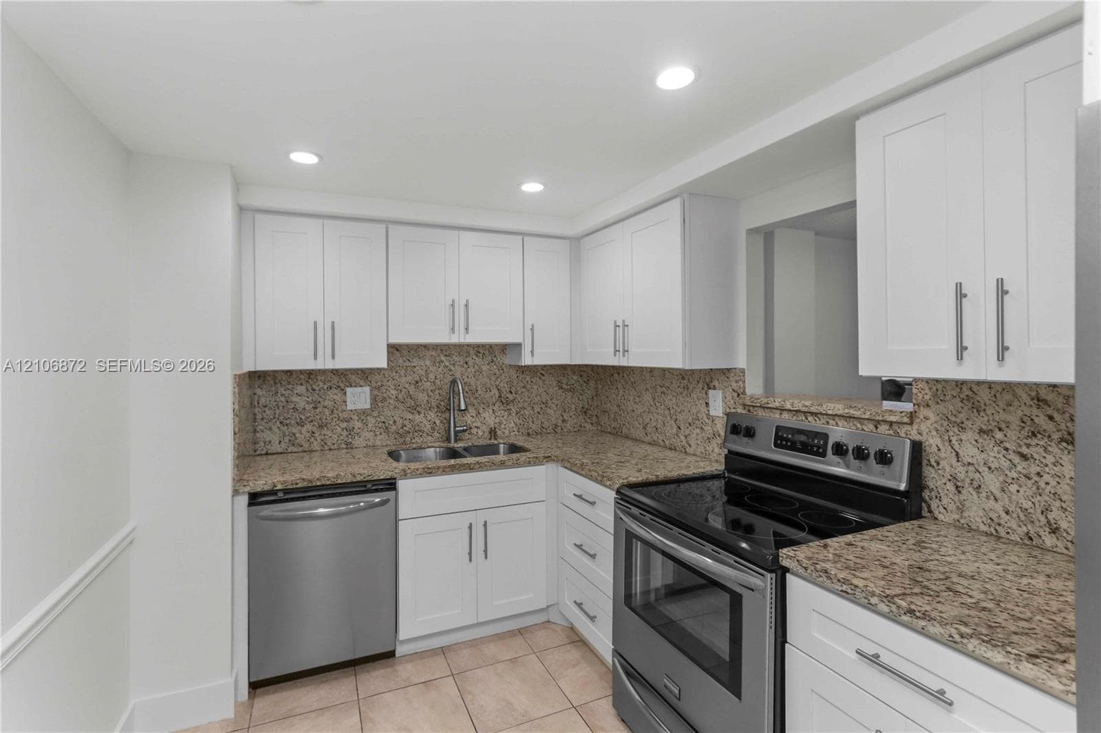 Kitchen featuring white Shaker-style cabinetry, stone countertops, stainless steel appliances, recessed lighting, and tile flooring