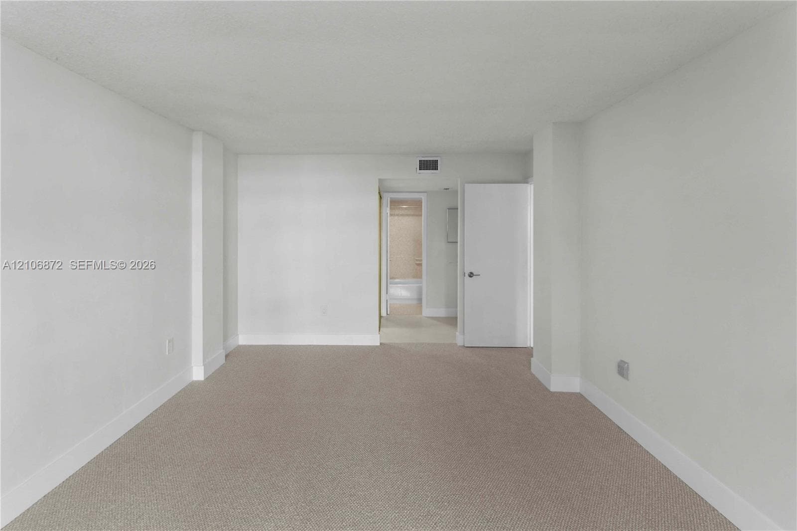 Neutral-toned carpeting, smooth-finish walls, and a solid-core interior door