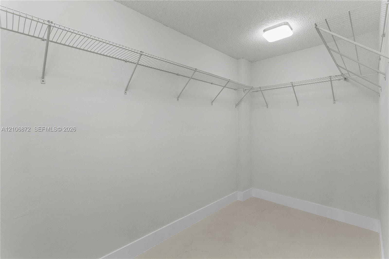 Walk-in storage space featuring neutral walls, ceiling-mounted lighting, and integrated wire shelving