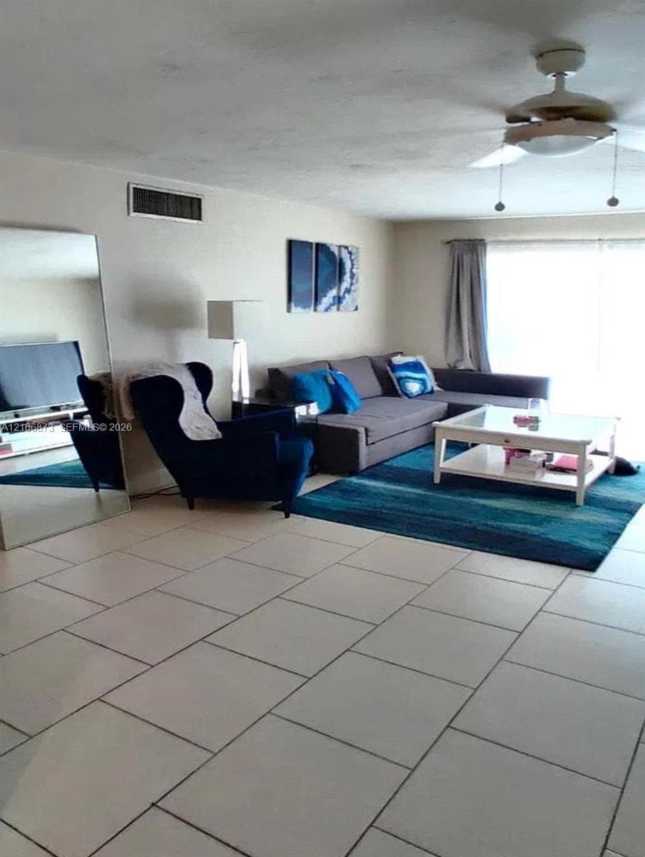Neutral tile flooring, ceiling fan with integrated light fixture, and large floor-to-ceiling sliding glass doors
