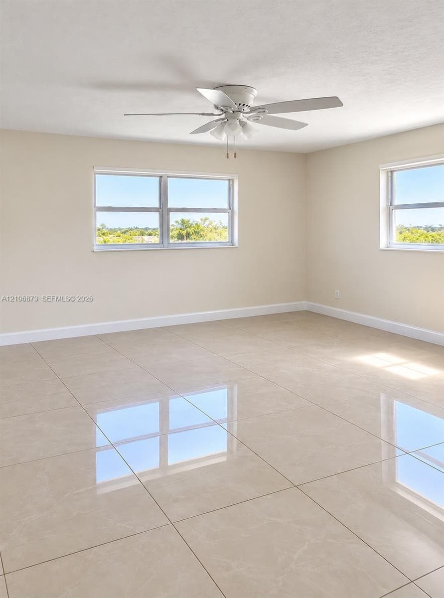 Large-format tile flooring, neutral wall tones, multi-pane windows, and a white ceiling fan with integrated lighting