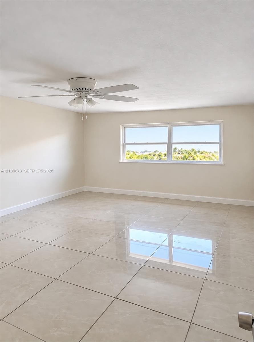 Neutral interior featuring large-format tile flooring, multi-pane window with outdoor scenery, and ceiling-mounted light fixture with a fan