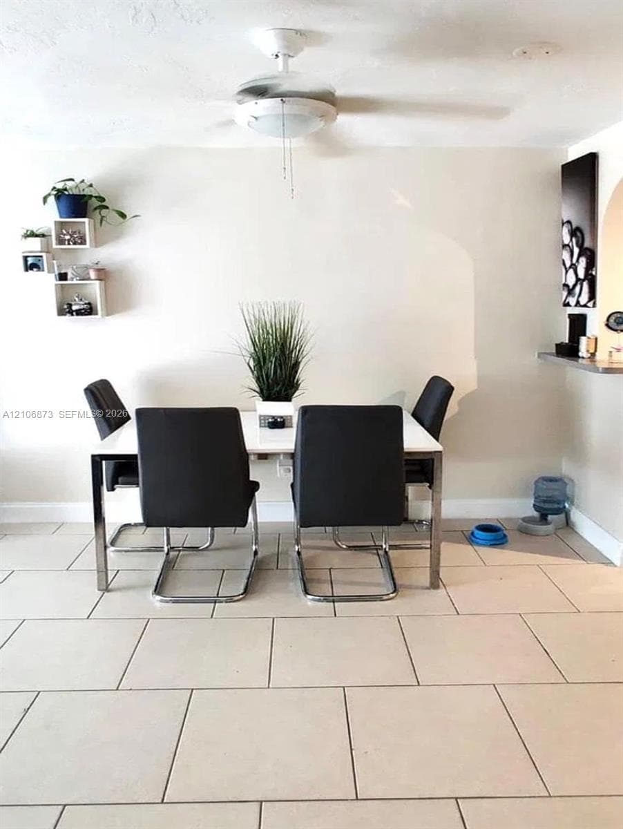 Large-format tile flooring, wall-mounted display shelving, and a ceiling-mounted light fixture with an integrated fan