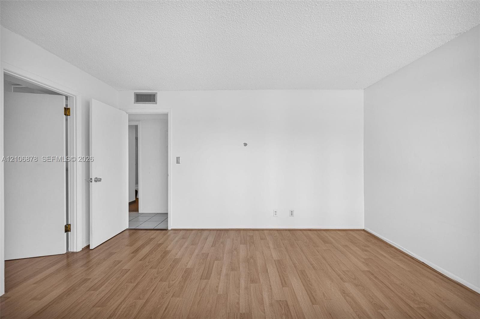 Interior space featuring wood-finish flooring, white walls, and interior swing doors with brushed metal hardware
