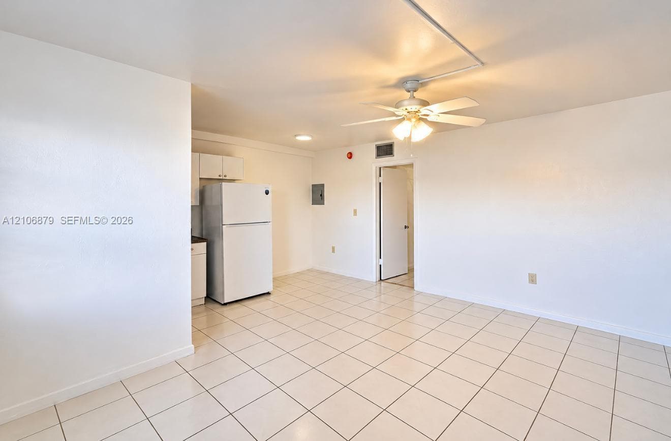 Interior space featuring tile flooring, a white refrigerator, and a ceiling fan with integrated light fixture
