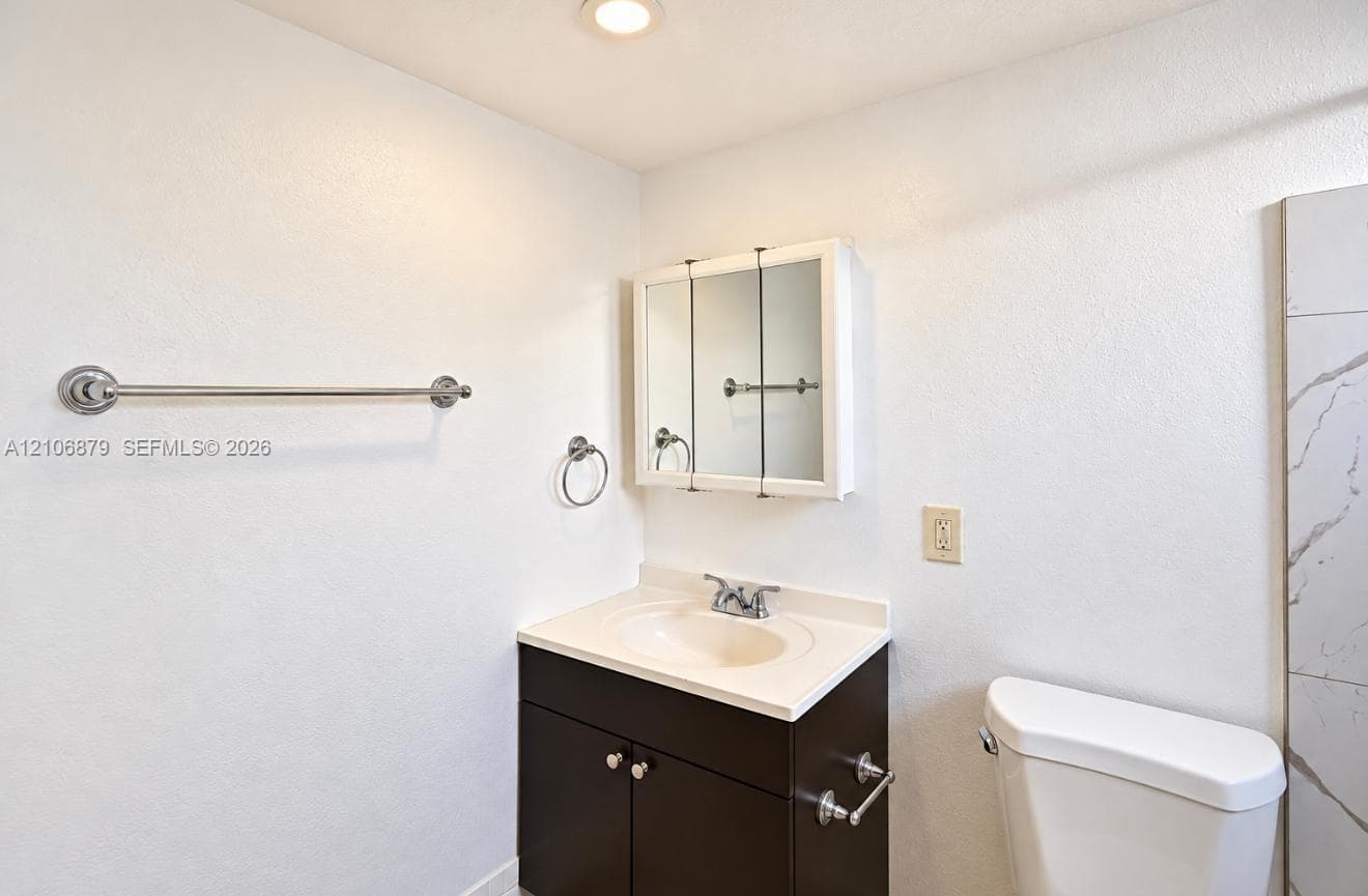 Bathroom vanity featuring a dark-finish base cabinet, integrated molded sink, tri-fold medicine cabinet, and chrome hardware throughout