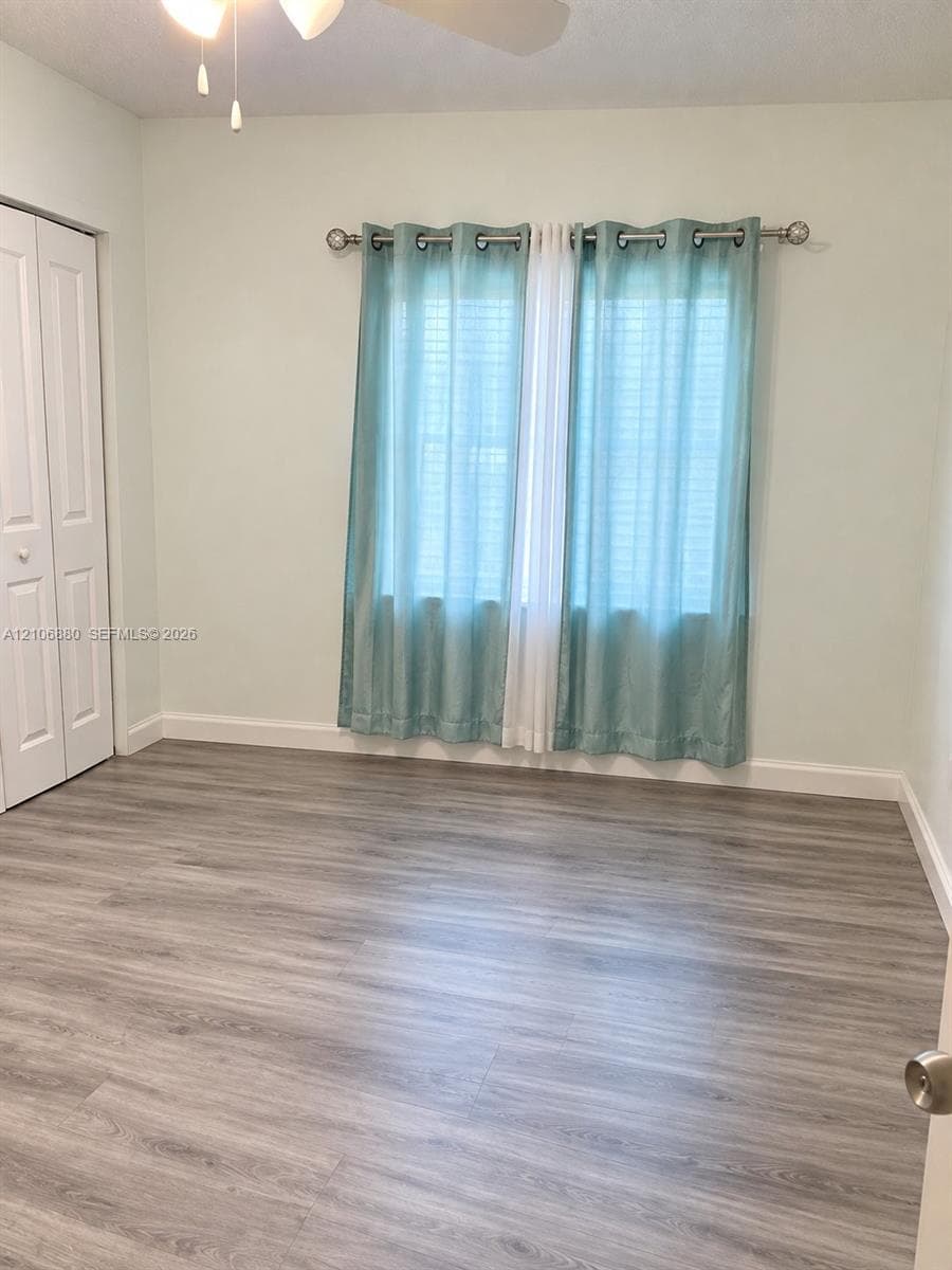 Wood-finish flooring, dual-panel closet doors, and a ceiling-mounted light fixture.