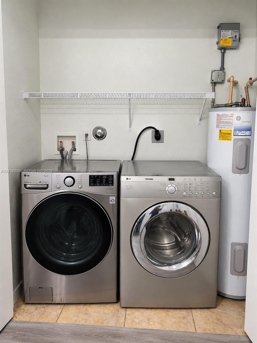 Laundry space featuring stainless steel front-load laundry appliances, a vertical water heater, and wire shelving.
