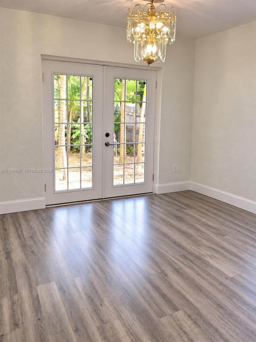 Wood-finish flooring, dual doors to outside, and a ceiling-mounted light fixture.