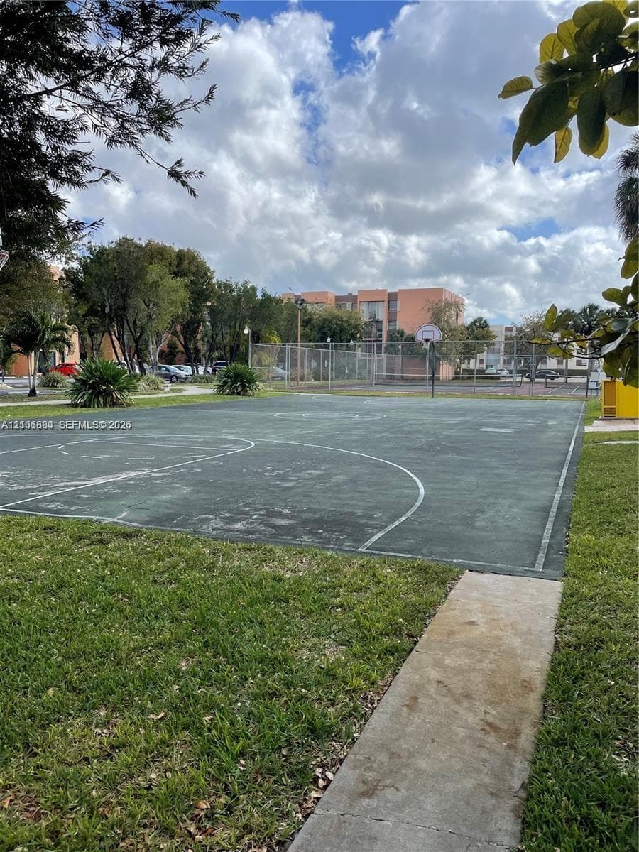 Outdoor basketball court with painted surface markings, chain-link fencing, and concrete walkway