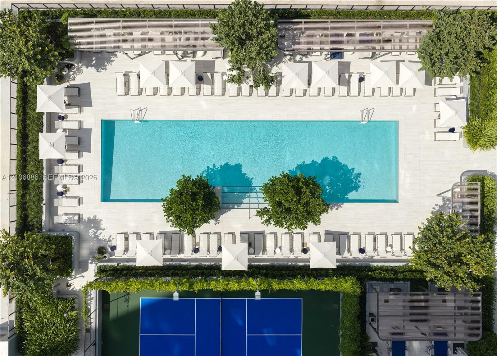 Rectangular swimming pool with tiled surround, pickleball court with hard surface, and perimeter landscaping