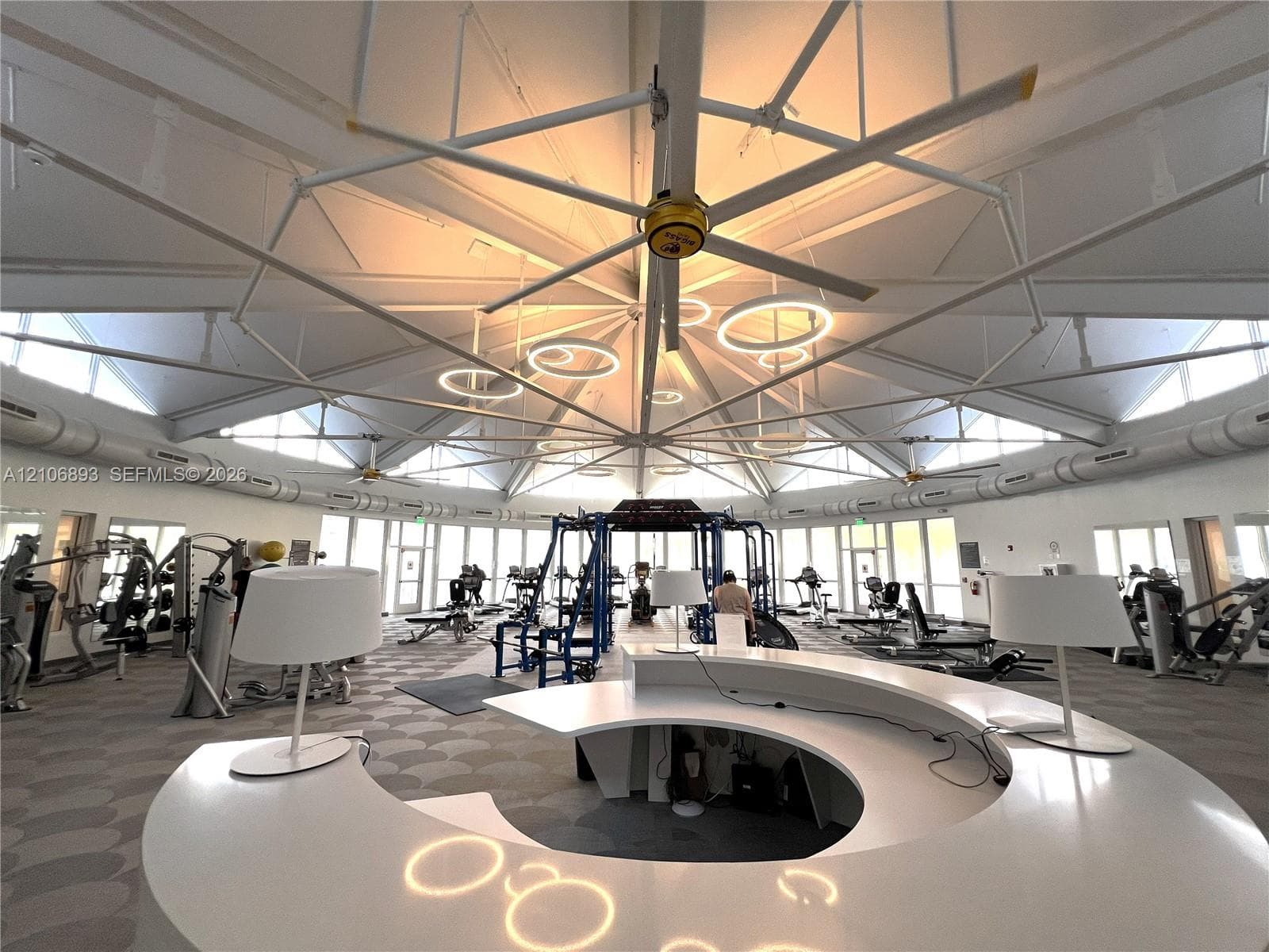 Expansive circular space featuring a radial exposed beam ceiling, large-scale structural windows, and a curved built-in reception desk