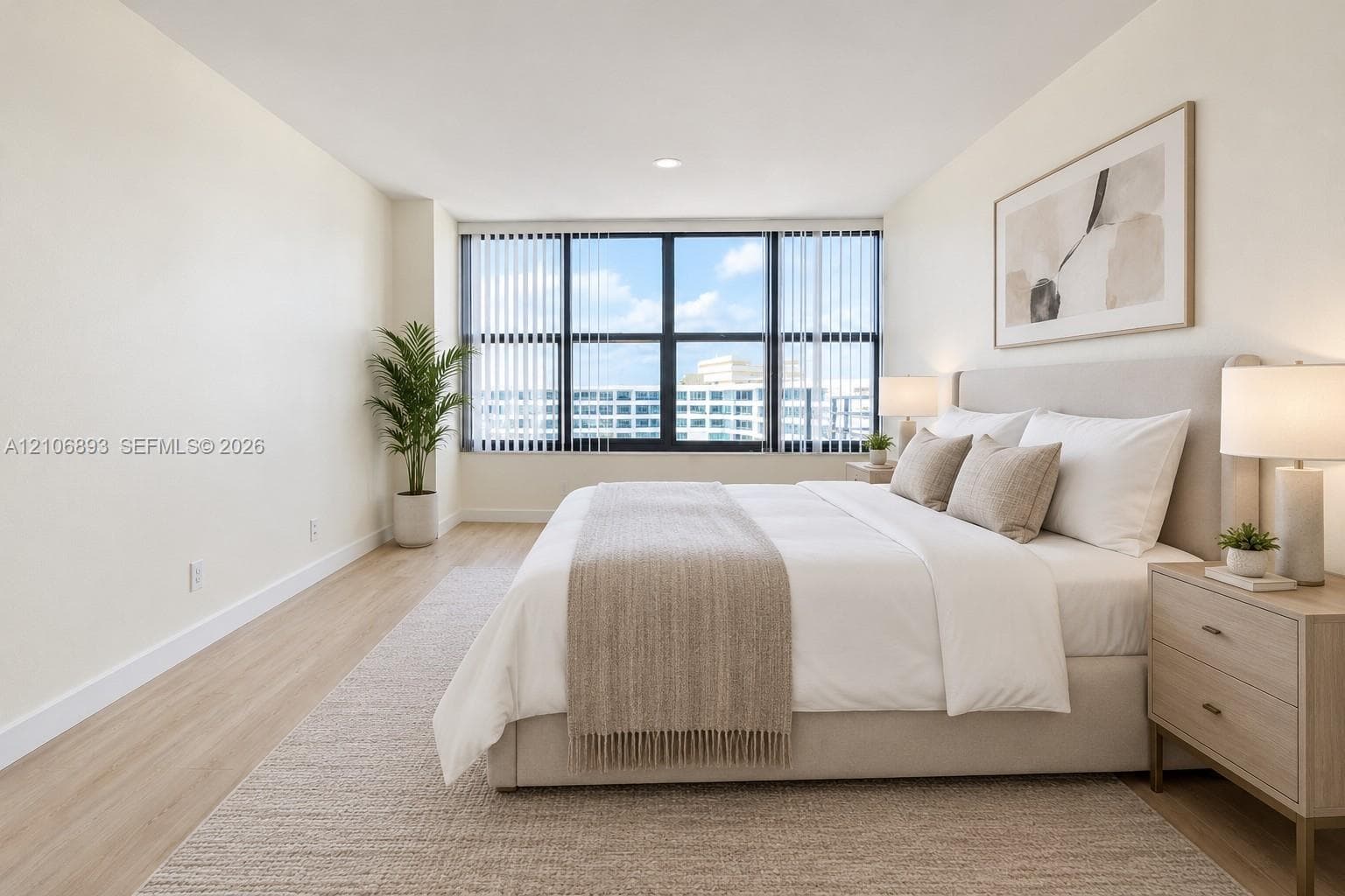Expansive window wall with black frames and integrated vertical blinds, recessed ceiling lighting, and neutral wood-finish flooring