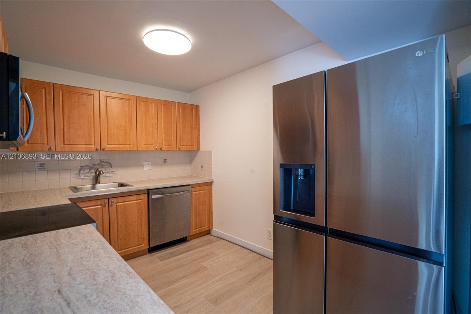 Kitchen featuring wood cabinetry, stone-finish countertops, stainless steel appliances, and wood-finish flooring
