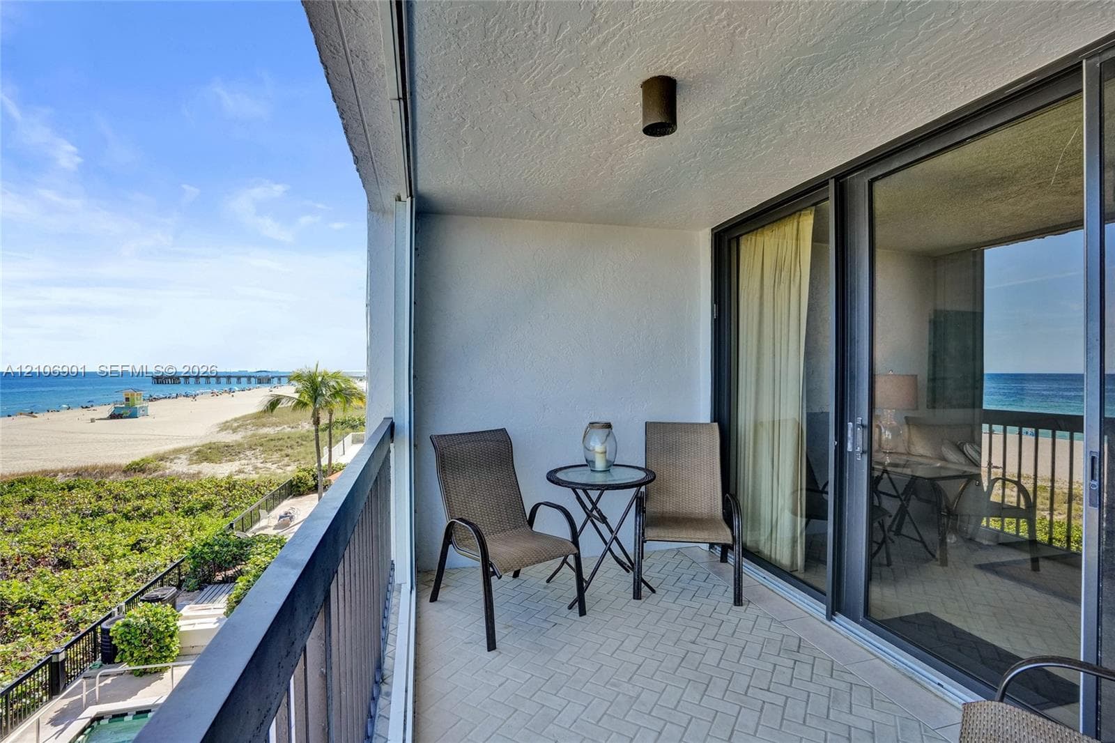 Covered balcony featuring herringbone-pattern tile flooring, dark metal railing, and direct access through large sliding glass doors