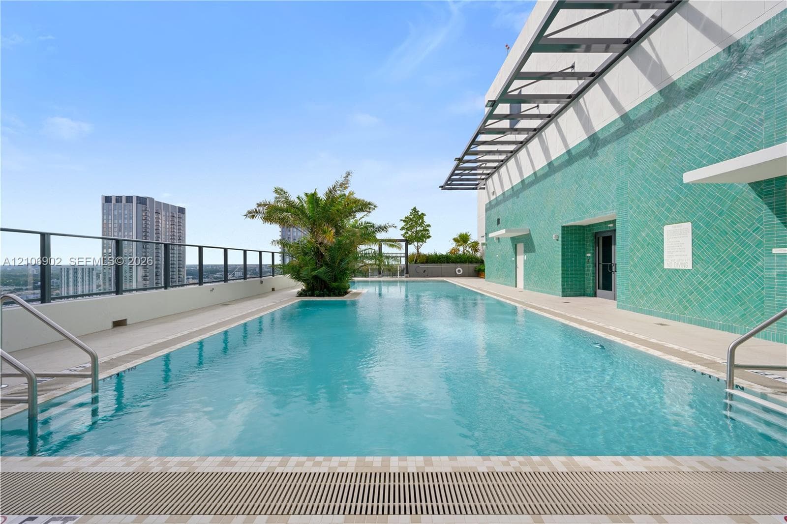 Rooftop swimming pool featuring a tiled accent wall, metal-frame pergola, integrated landscaping, and metal perimeter railing