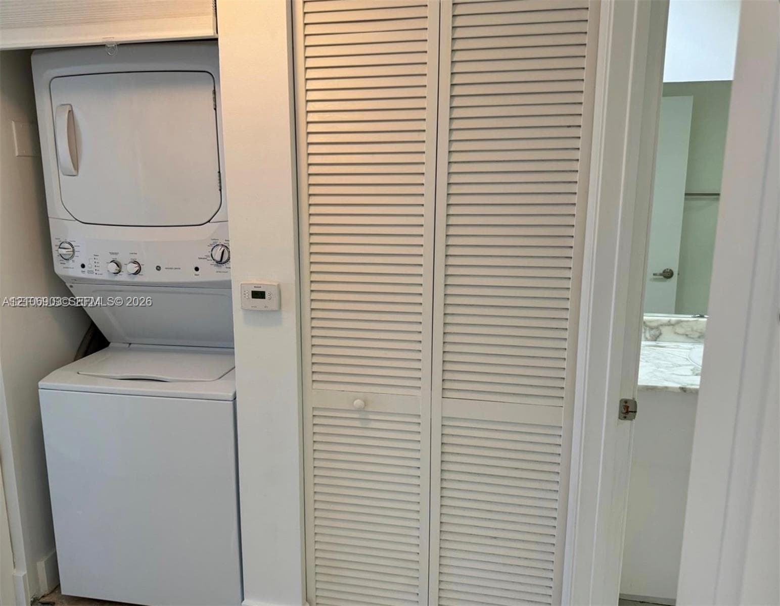 Stacked washer and dryer unit with louvered bi-fold closet doors