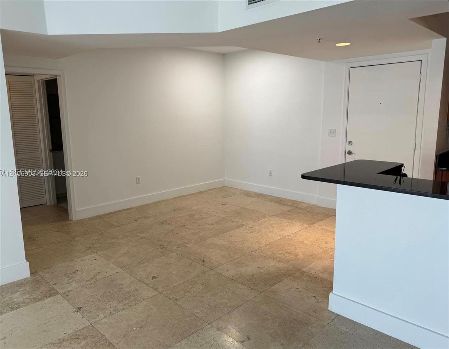 Open interior space featuring high vaulted ceilings, large-format tile flooring, and a breakfast bar with a solid surface countertop